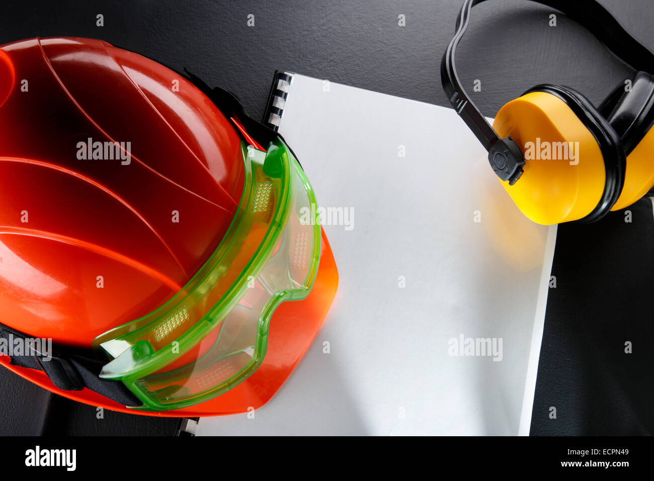 Occhiali di sicurezza, auricolari e casco rosso in primo piano Foto Stock