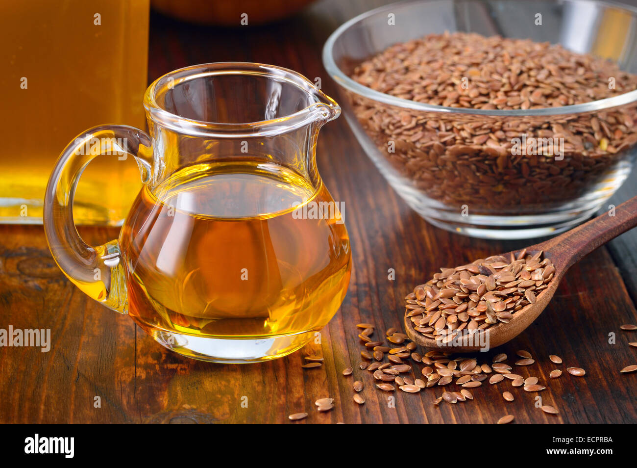 Brown semi di lino sul cucchiaio e olio di lino in caraffa di vetro su un tavolo di legno. Olio di lino è ricco in acido grasso omega-3. Foto Stock