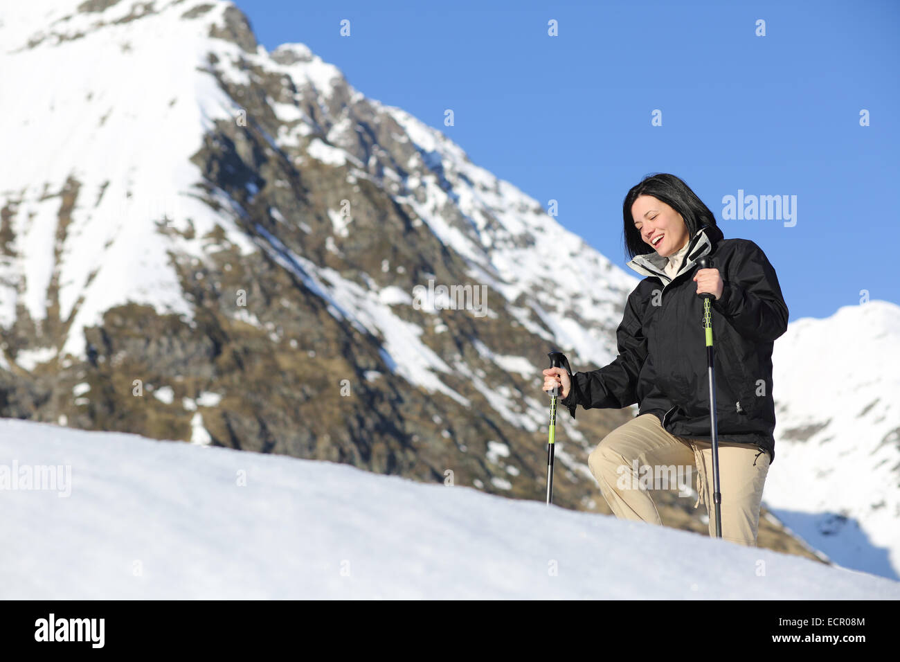 Felice escursionista woman trekking sulla neve in montagna con una montagna innevata in background Foto Stock