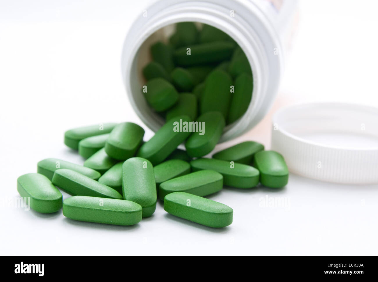 Queste sono le compresse di vitamina. Le compresse di colore verde sono presi al di fuori della bottiglia bianca. Foto Stock