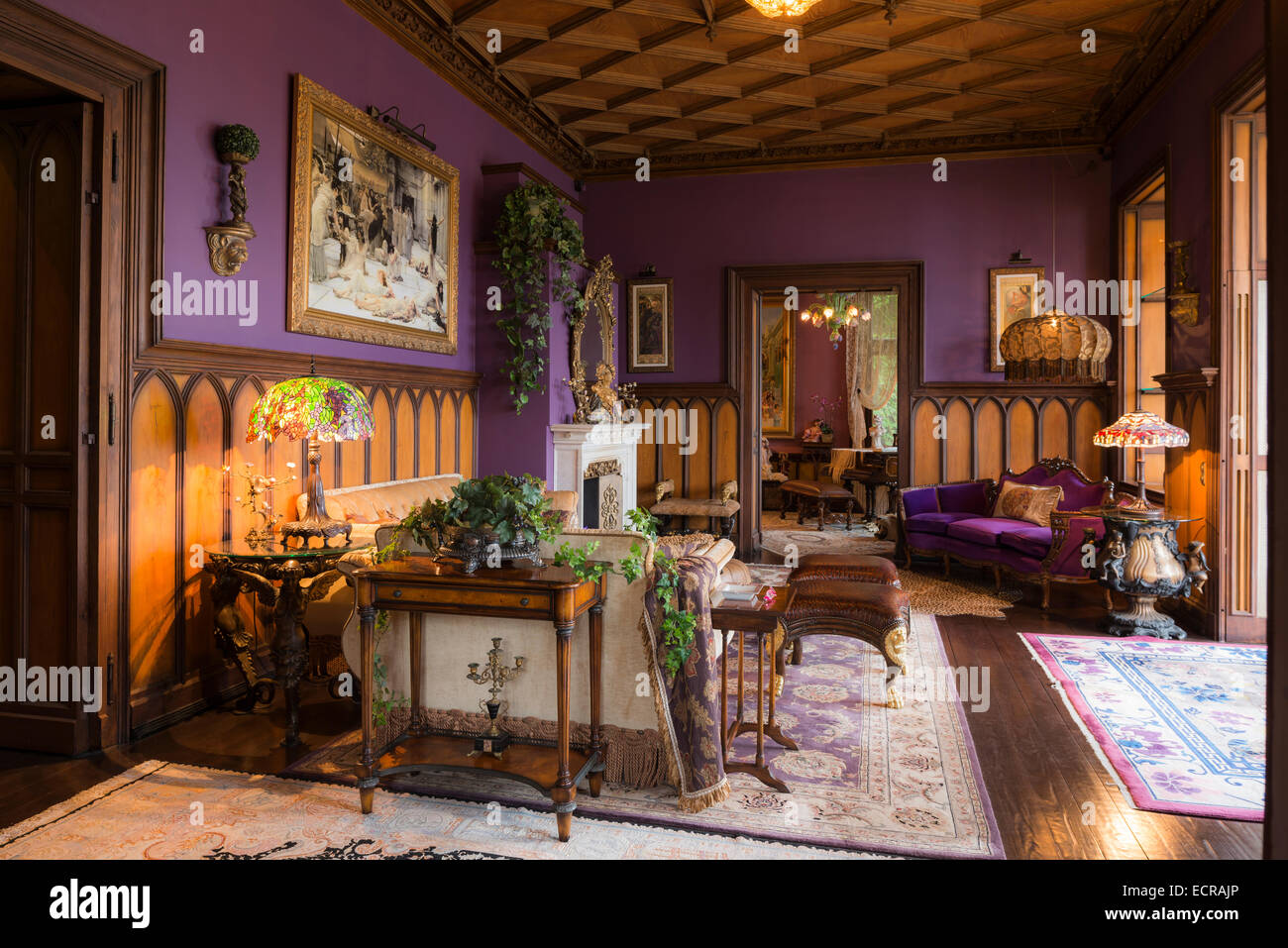 Il legno del soffitto a cassettoni in castello soggiorno con pareti di lilla e sfarzosa tappeti Foto Stock
