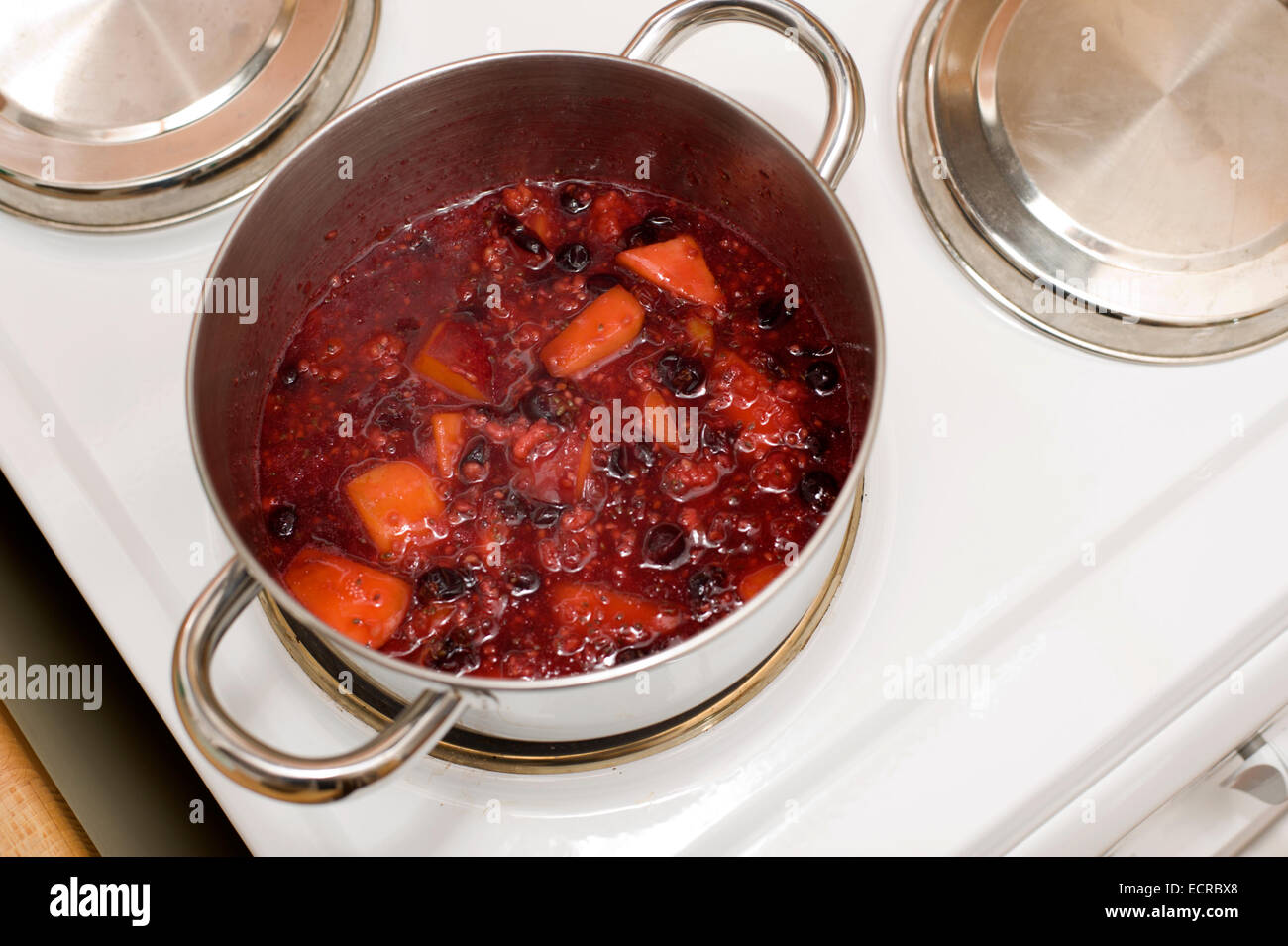 Una pentola bollente frutto di essere ridotta in preparazione per la realizzazione di marmellate e torte di alcuni e sminuzzare ripieni Foto Stock