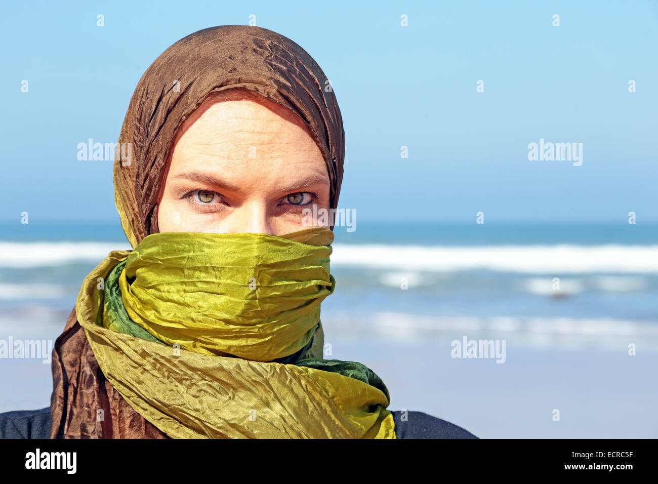 Bella donna araba con sciarpa verde all'oceano Foto Stock