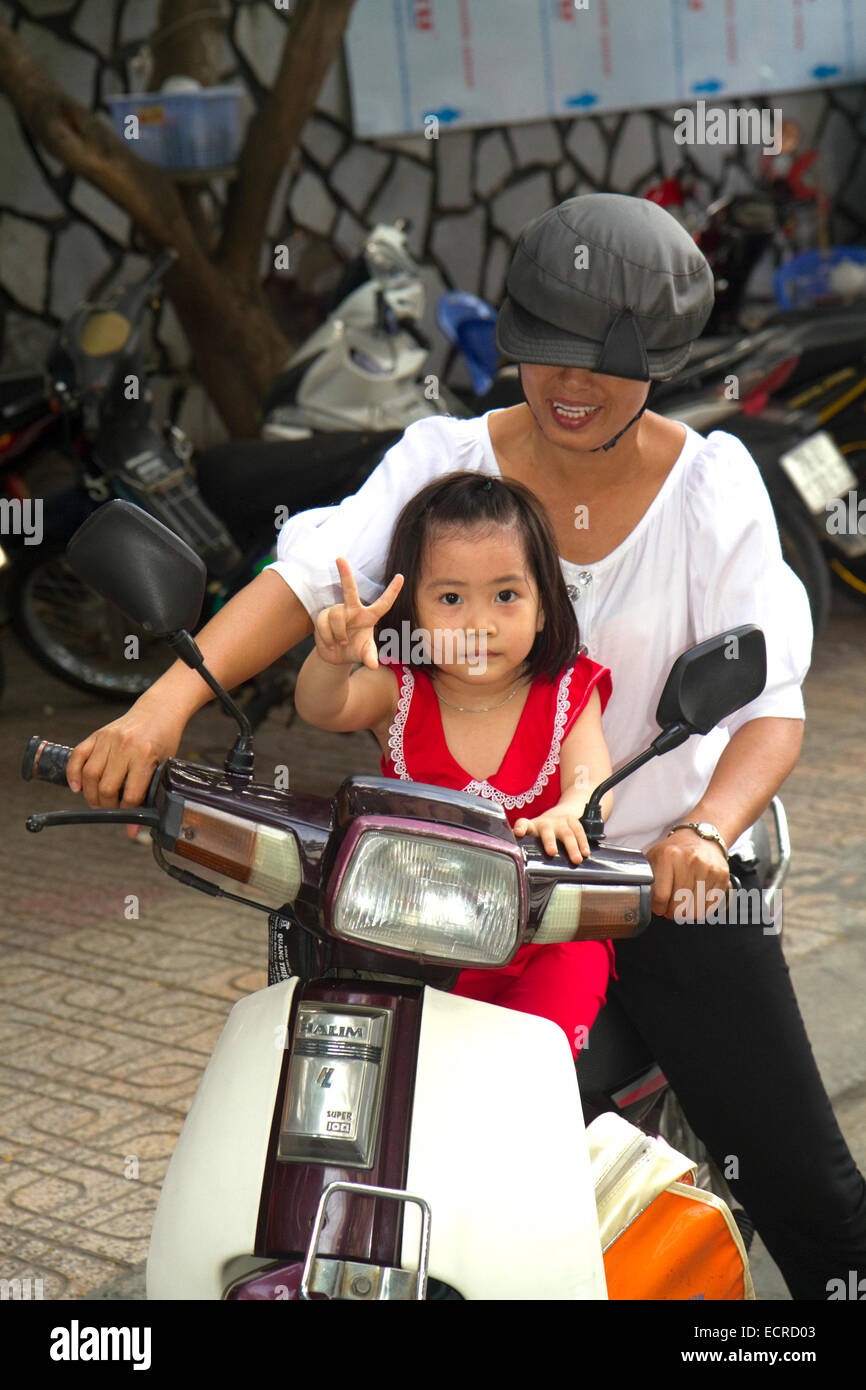 La madre e il bambino in sella a una moto-scooter insieme a Nha Trang, Vietnam. Foto Stock