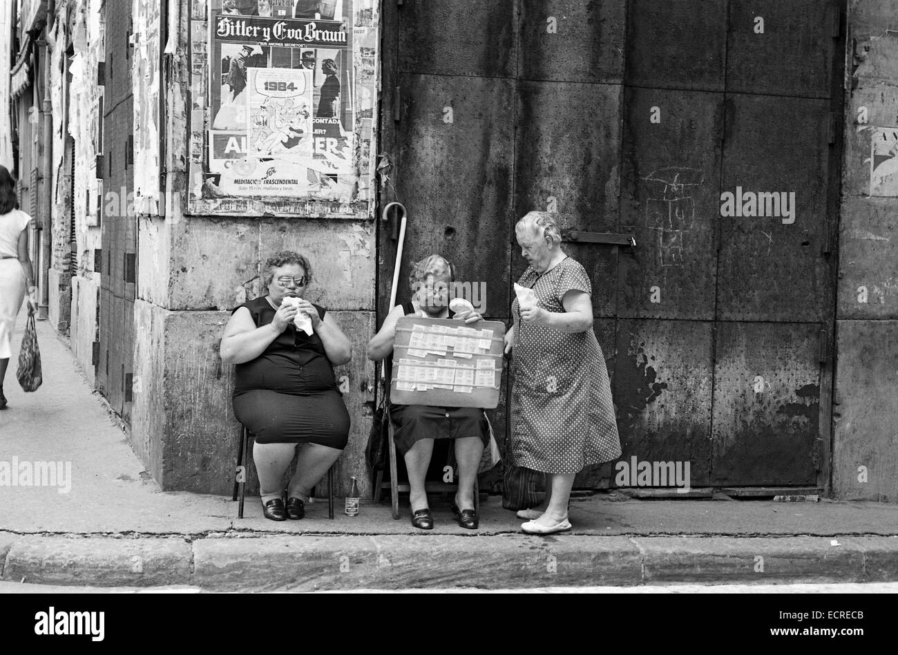 Una vecchia donna compri una tradizionale lotteria spagnola ad un cieco di donna che mangia un panino in agosto, 1982 a Valencia, in Spagna. Nero a Foto Stock