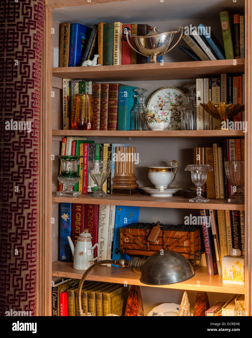 Un assortimento di libri, bicchieri e posate su open scaffali in legno Foto Stock