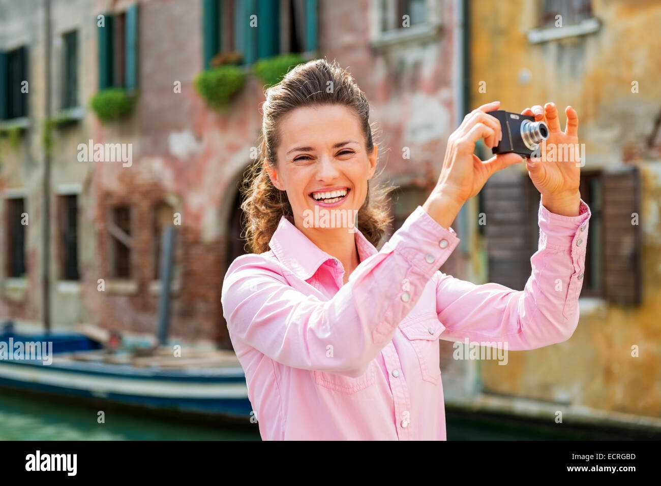 Sorridente giovane donna prendendo foto a venezia, Italia Foto Stock