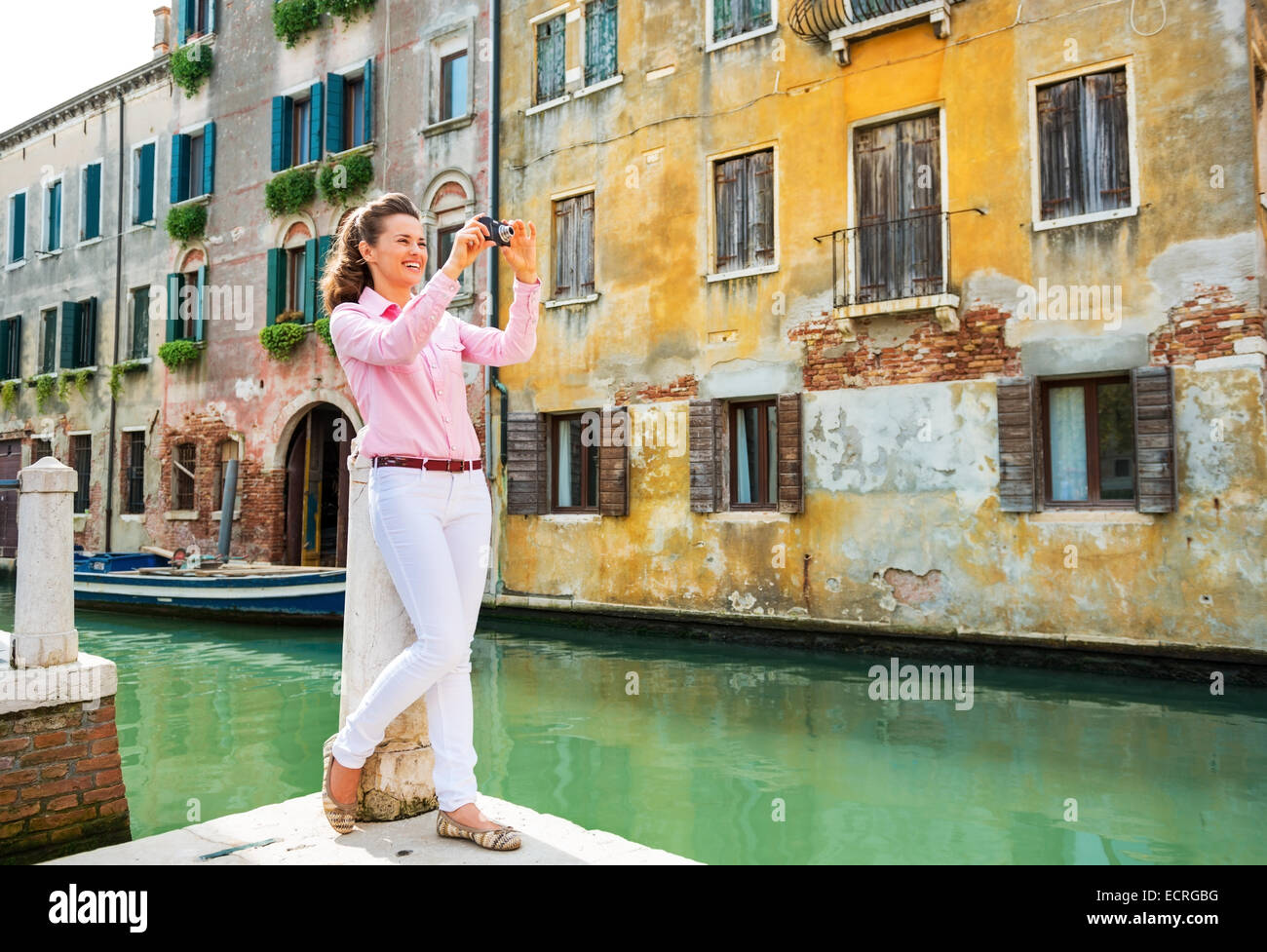 A piena lunghezza Ritratto di felice giovane donna prendendo foto a venezia, Italia Foto Stock