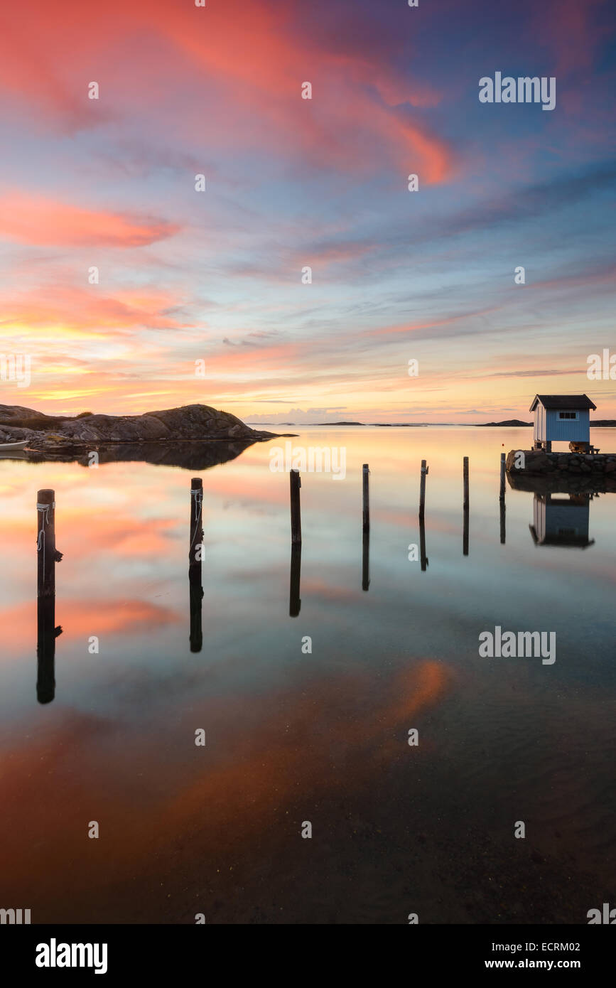 Piccolo capanno di pesca e posti di legno in un lago al tramonto Foto Stock