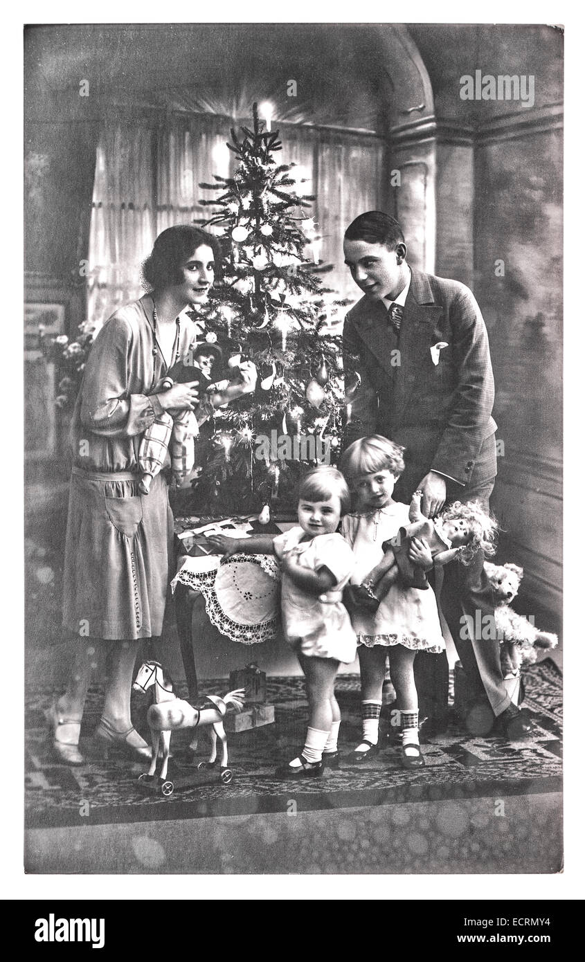 Antico ritratto di famiglia dei genitori e dei bambini con albero di natale. vintage immagine originale con grana di pellicola e la sfocatura. un nero Foto Stock