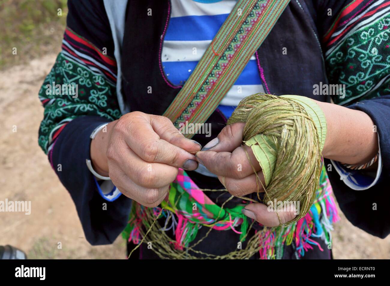 Una mano di donna Hmong gira la canapa prima di morirlo nero e tessendo i tradizionali indumenti Hmong Foto Stock