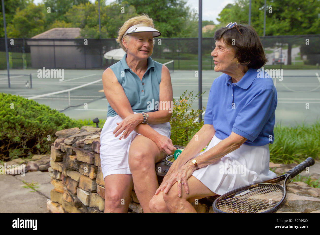 Due senior donna amici parlando a campi da tennis Foto Stock