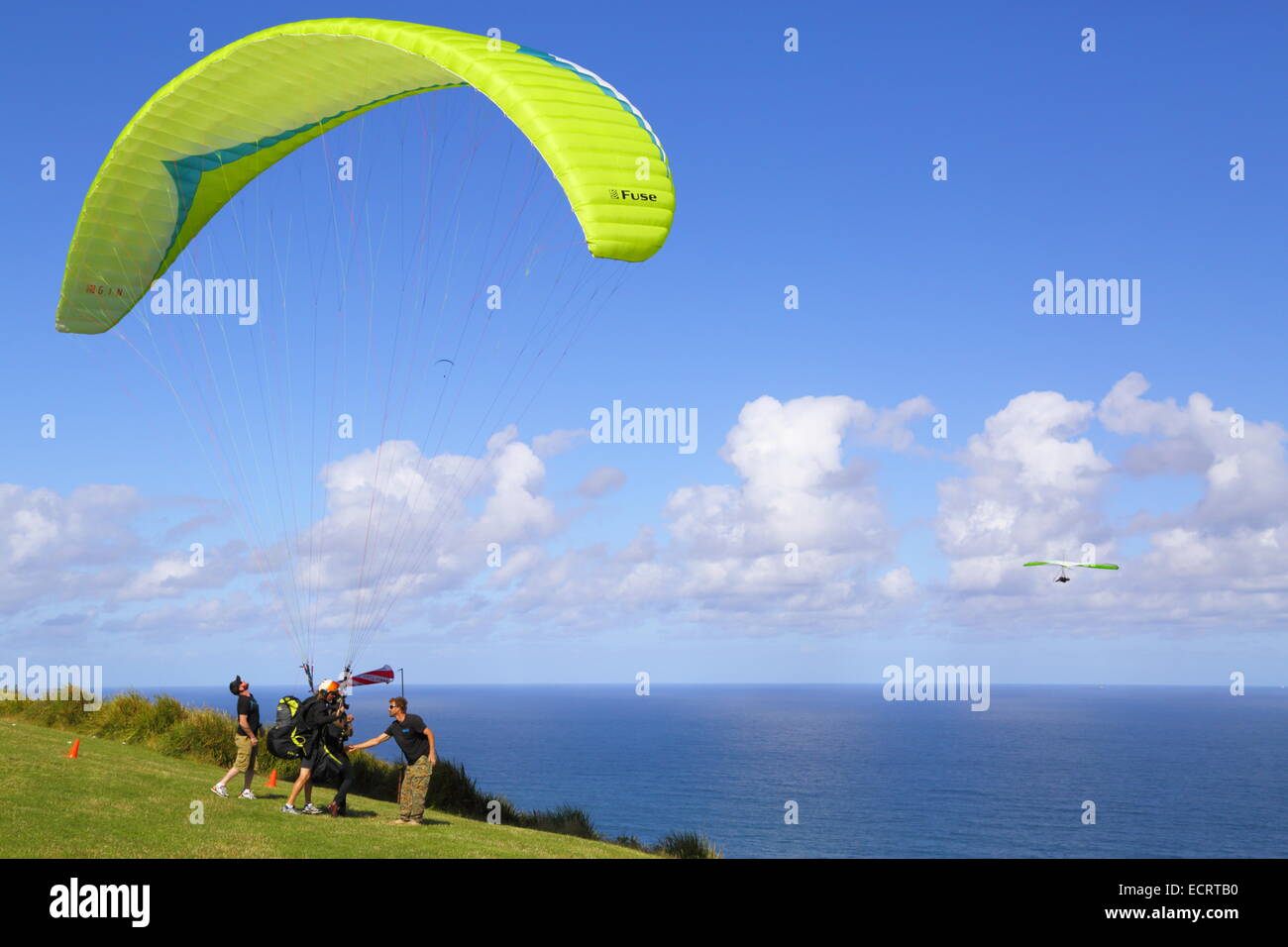 Un parapendio in tandem si prepara a sollevare oltre l'Oceano Pacifico a Bald Hill, Nuovo Galles del Sud, Australia. Foto Stock