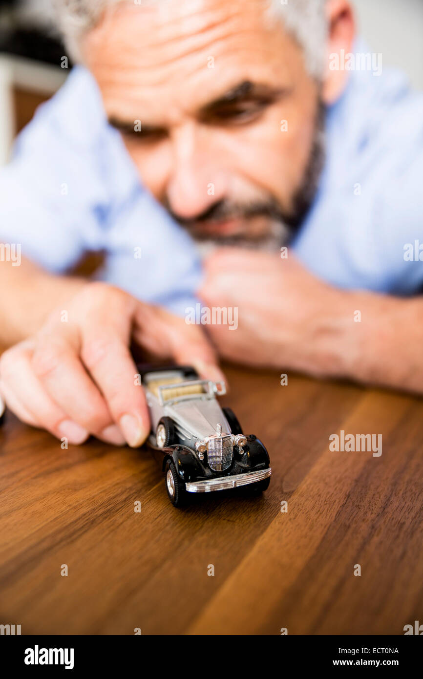 L'uomo gioca con automobili giocattolo Foto Stock