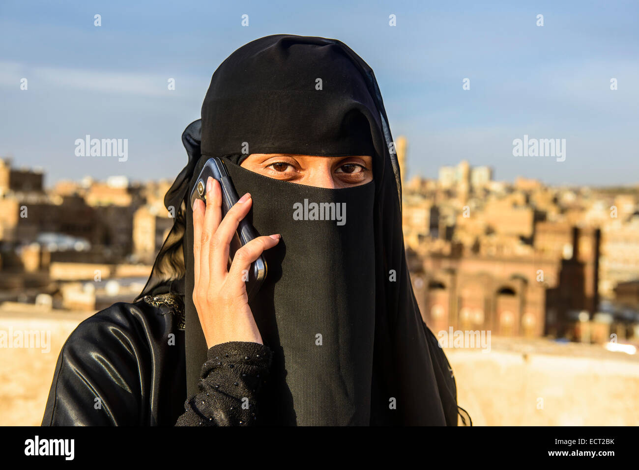 Velò giovane donna sul suo cellulare, nella città vecchia, Sana'a, Yemen Foto Stock