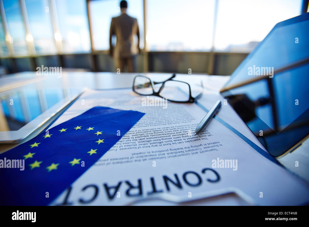 Contratto internazionale con la penna, bandiera dell Unione Europea, digitali compresse e occhiali con lavoratore di ufficio su sfondo Foto Stock