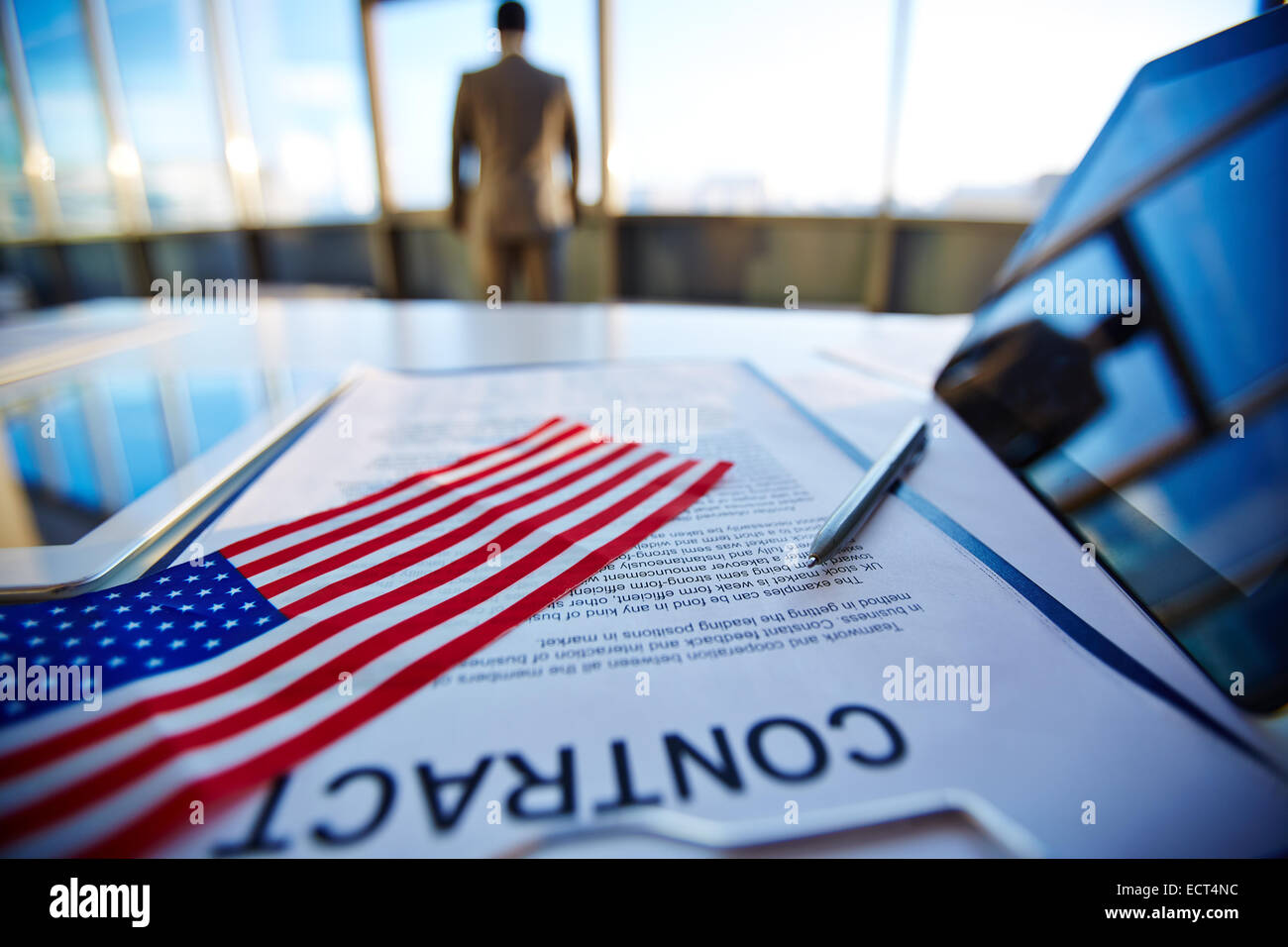 Accordo commerciale con penna, bandiera americana e digital compresse con il lavoratore di ufficio su sfondo Foto Stock