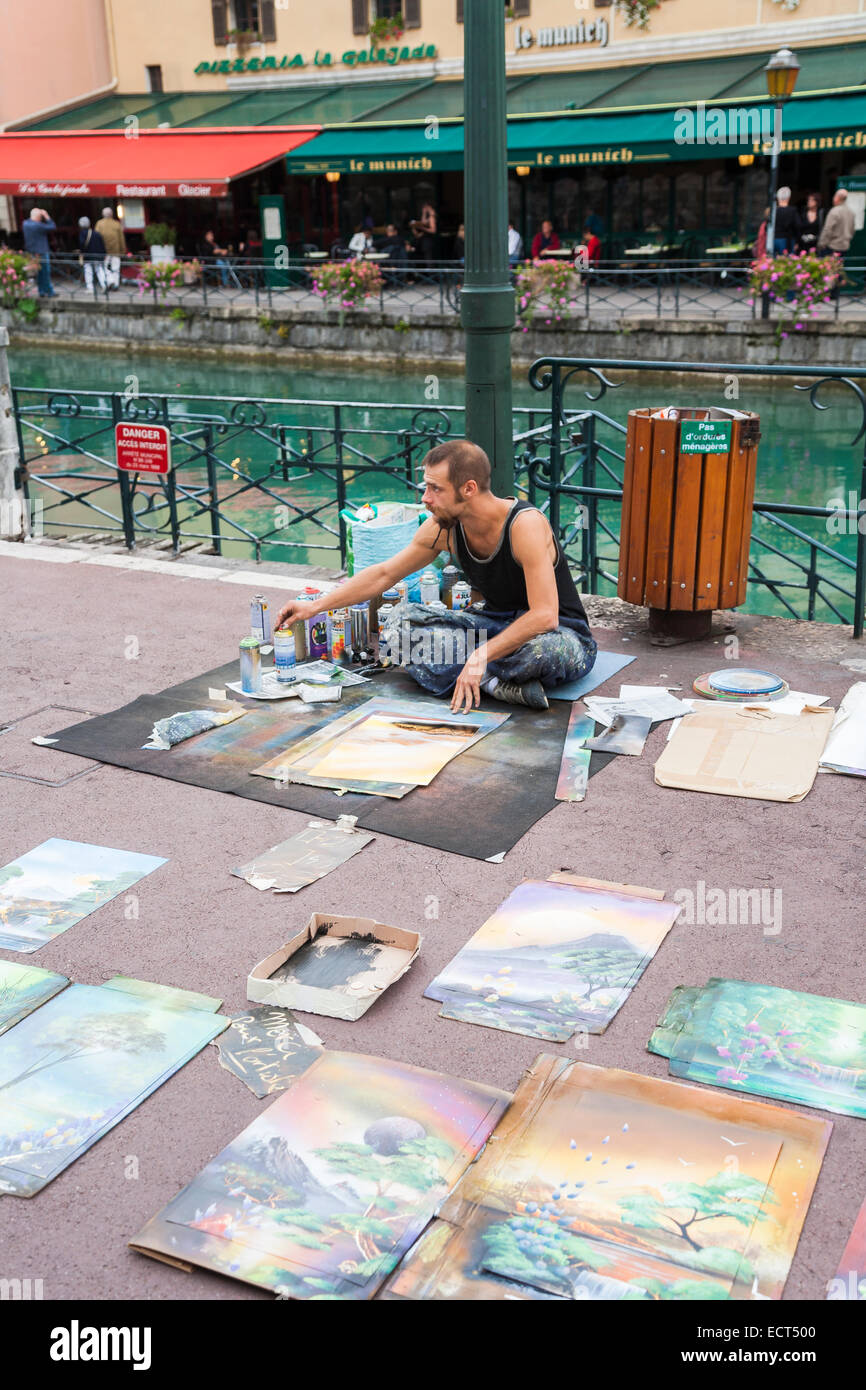 Stile di vita: Artista di strada francese che vende fotografie colorate a spruzzo per souvenir turistici sul marciapiede vicino al fiume Thiou, Annecy, Francia Foto Stock