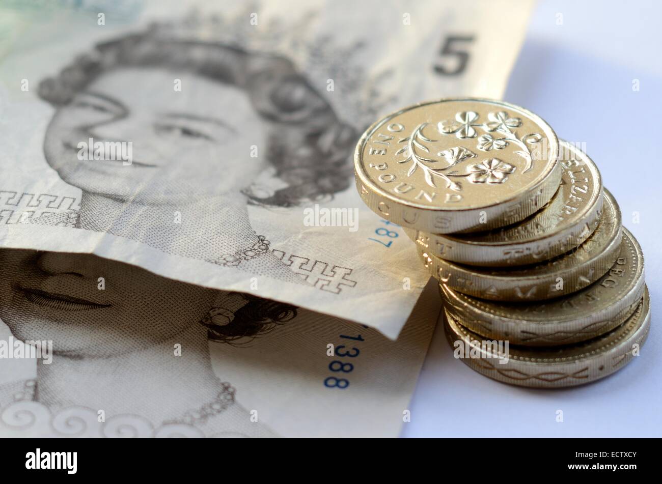 Pila di denaro, sterlina monete e £5 note Foto Stock