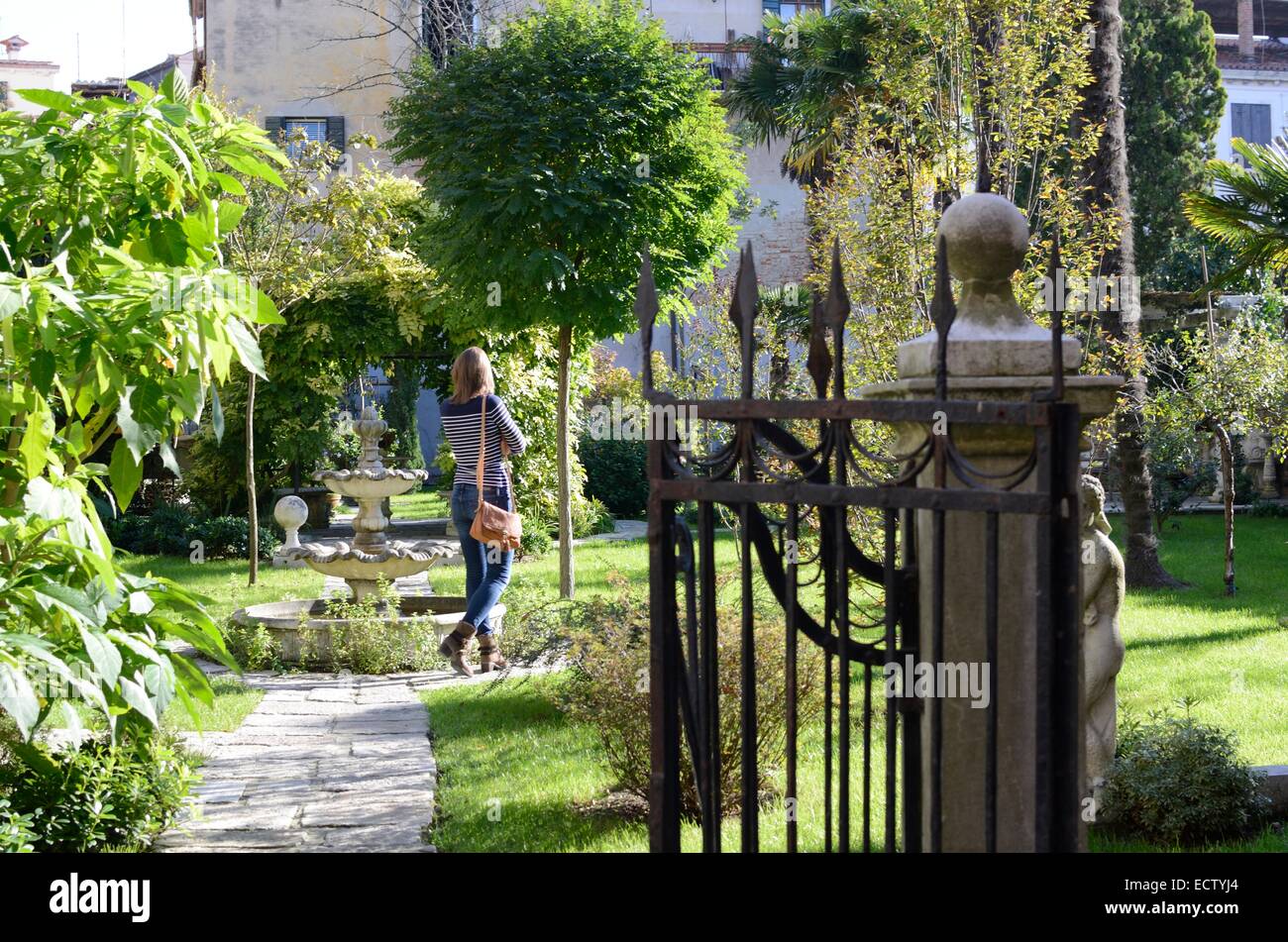 Giovane donna a piedi attraverso i giardini Foto Stock