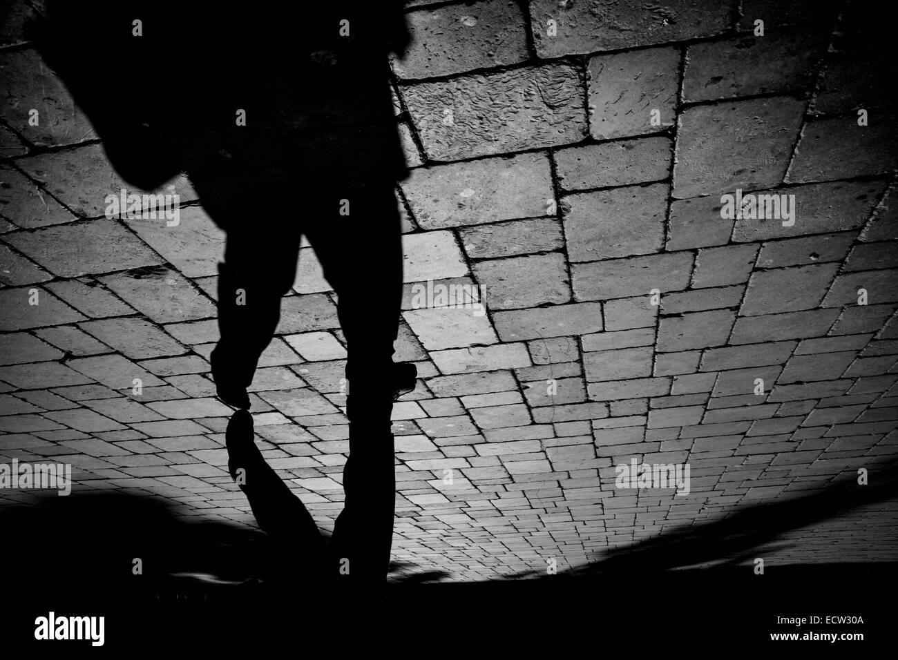 Una immagine monocromatica dell'ombra di una persona su un lastricato in pietra plaza a Gibilterra. Un elevato contrasto, la luce e l'ombra dell'immagine. Foto Stock