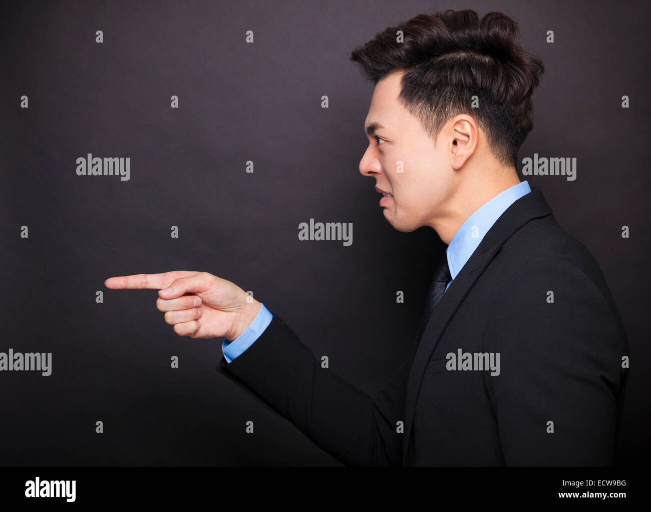 Vista laterale angry businessman in piedi prima di sfondo nero Foto Stock