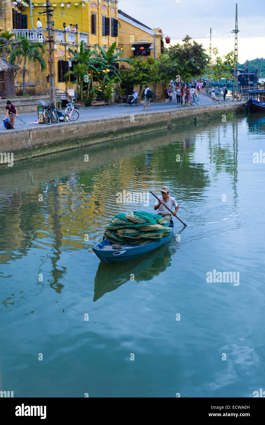 L'uomo le barche a remi su Thu Bon River, Hoi An al crepuscolo Foto Stock