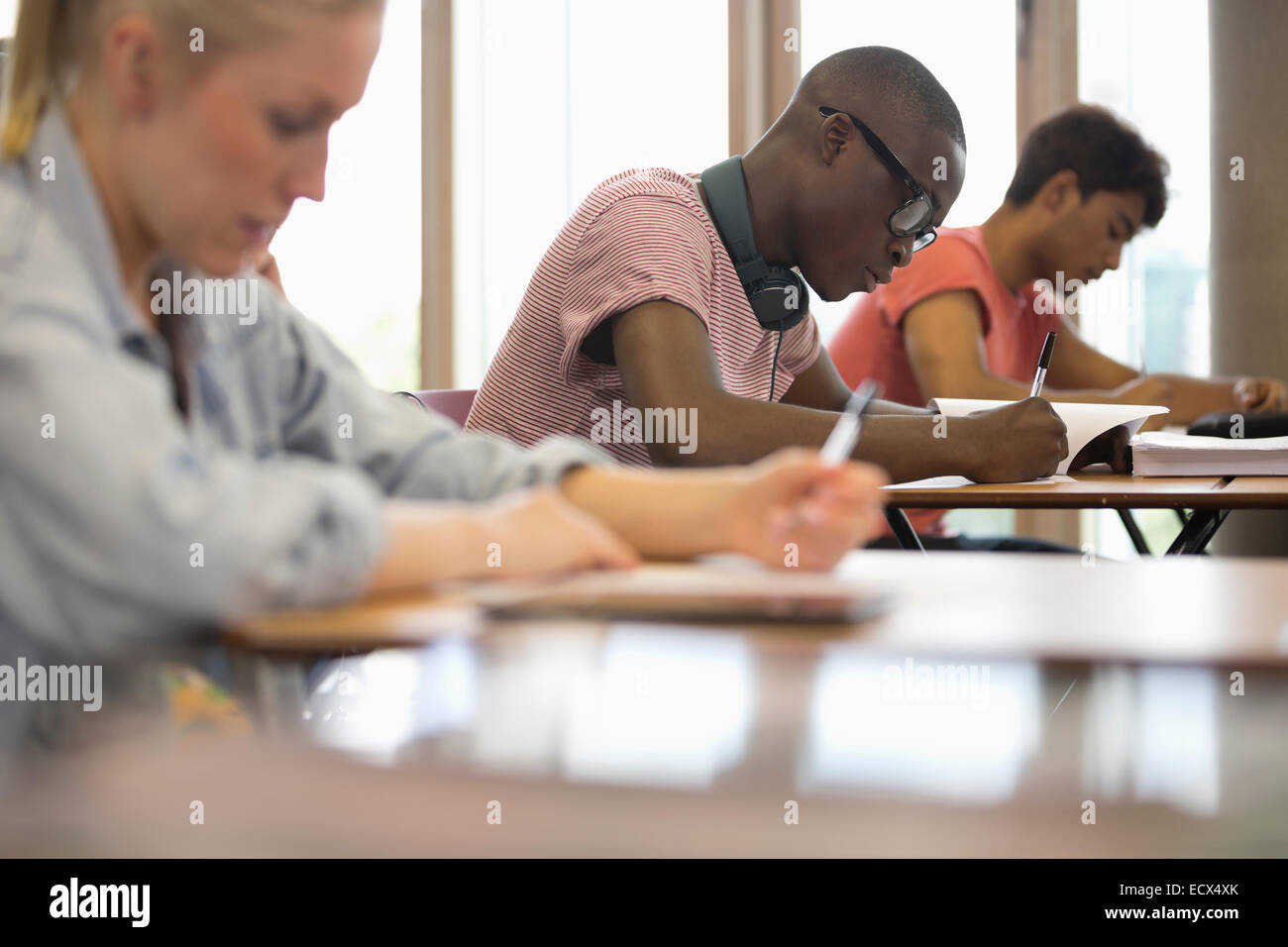 Vista di studenti seduti alla scrivania durante il test in aula Foto Stock