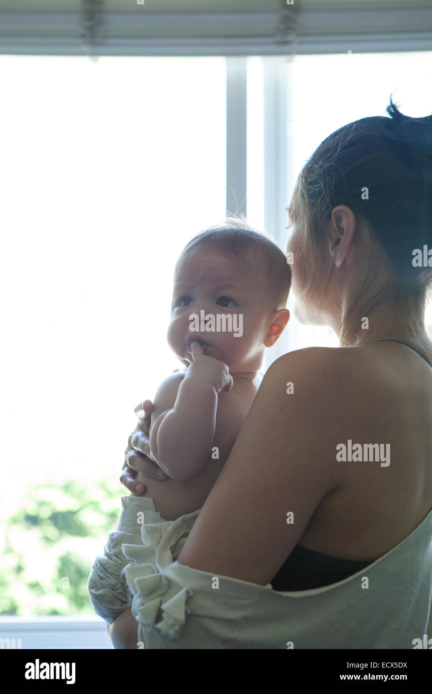 Azienda madre little baby e guardando attraverso la finestra Foto Stock