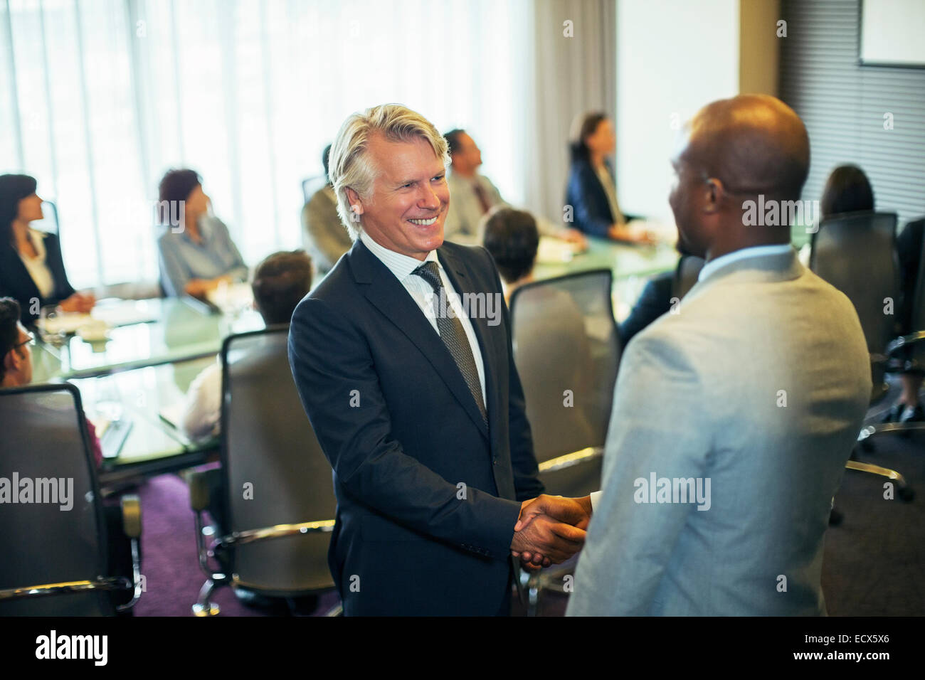 Imprenditori sorridenti si stringono la mano durante la riunione nella sala conferenze Foto Stock