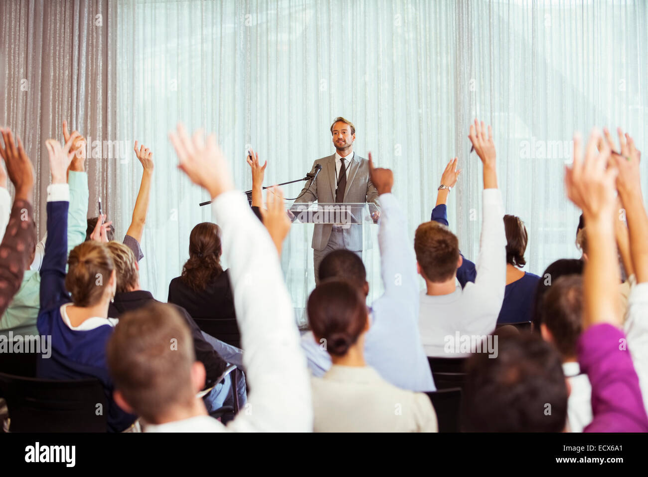 Imprenditore dando una presentazione in sala conferenze, persone alzando le mani Foto Stock