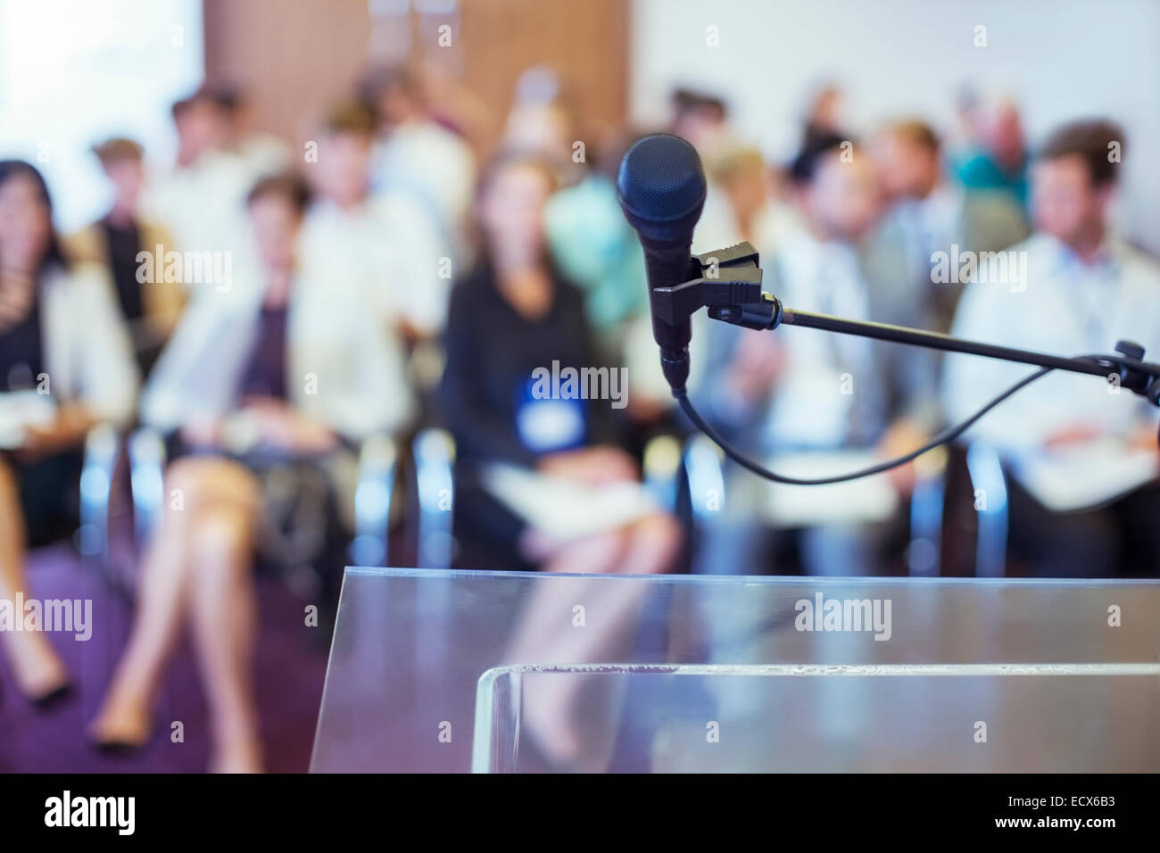 Close-up di microfono e leggio trasparente con il pubblico vede in sfondo sfocato Foto Stock