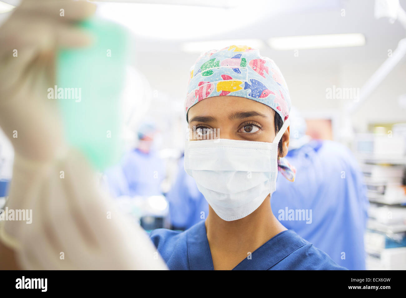 Chirurgo mascherato regolazione della sacca di soluzione fisiologica durante la chirurgia Foto Stock