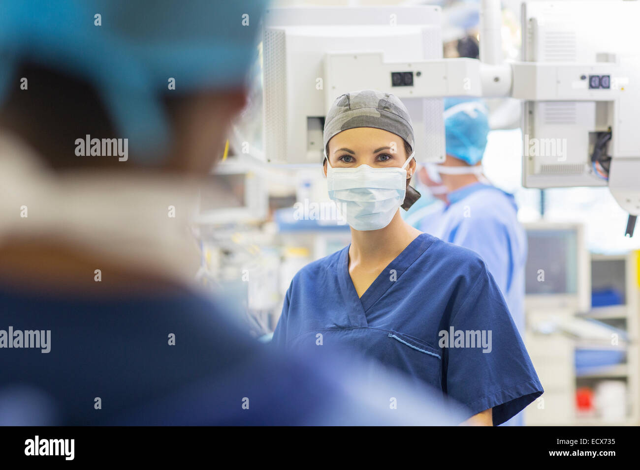 Medico donna che indossa il cappuccio chirurgico e maschera e guardando la fotocamera Foto Stock