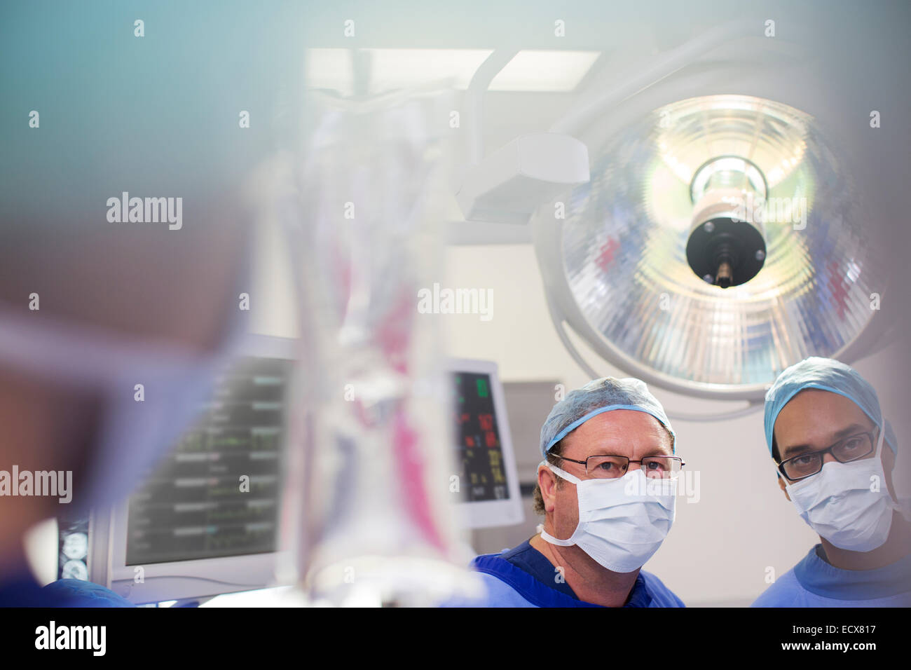 Due chirurghi guardando alla sacca di soluzione fisiologica durante la chirurgia Foto Stock