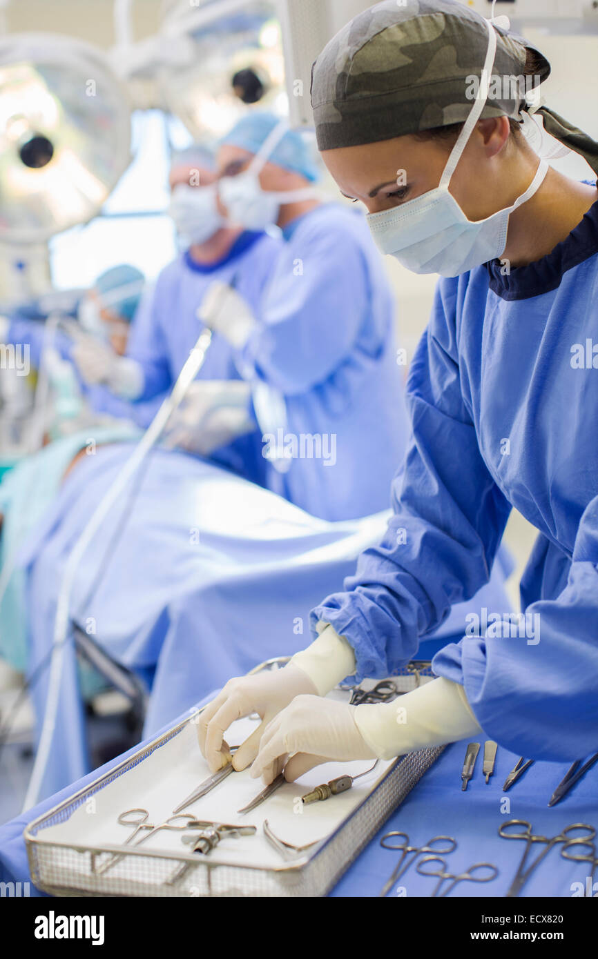 L'infermiera in piedi dal vassoio con gli strumenti chirurgici in sala operatoria Foto Stock