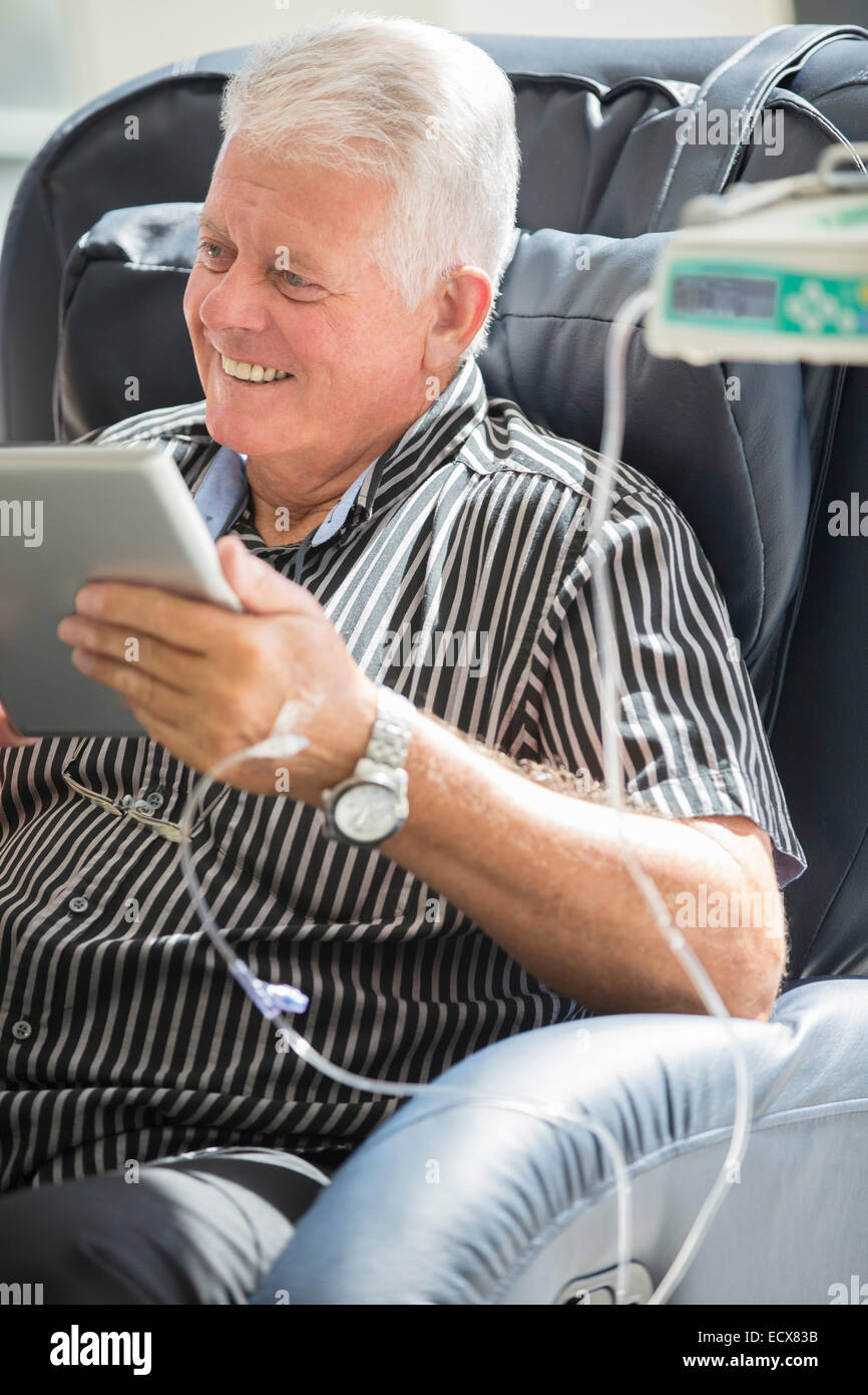 Senior uomo utilizzando tablet pc durante la ricezione di infusione endovenosa Foto Stock