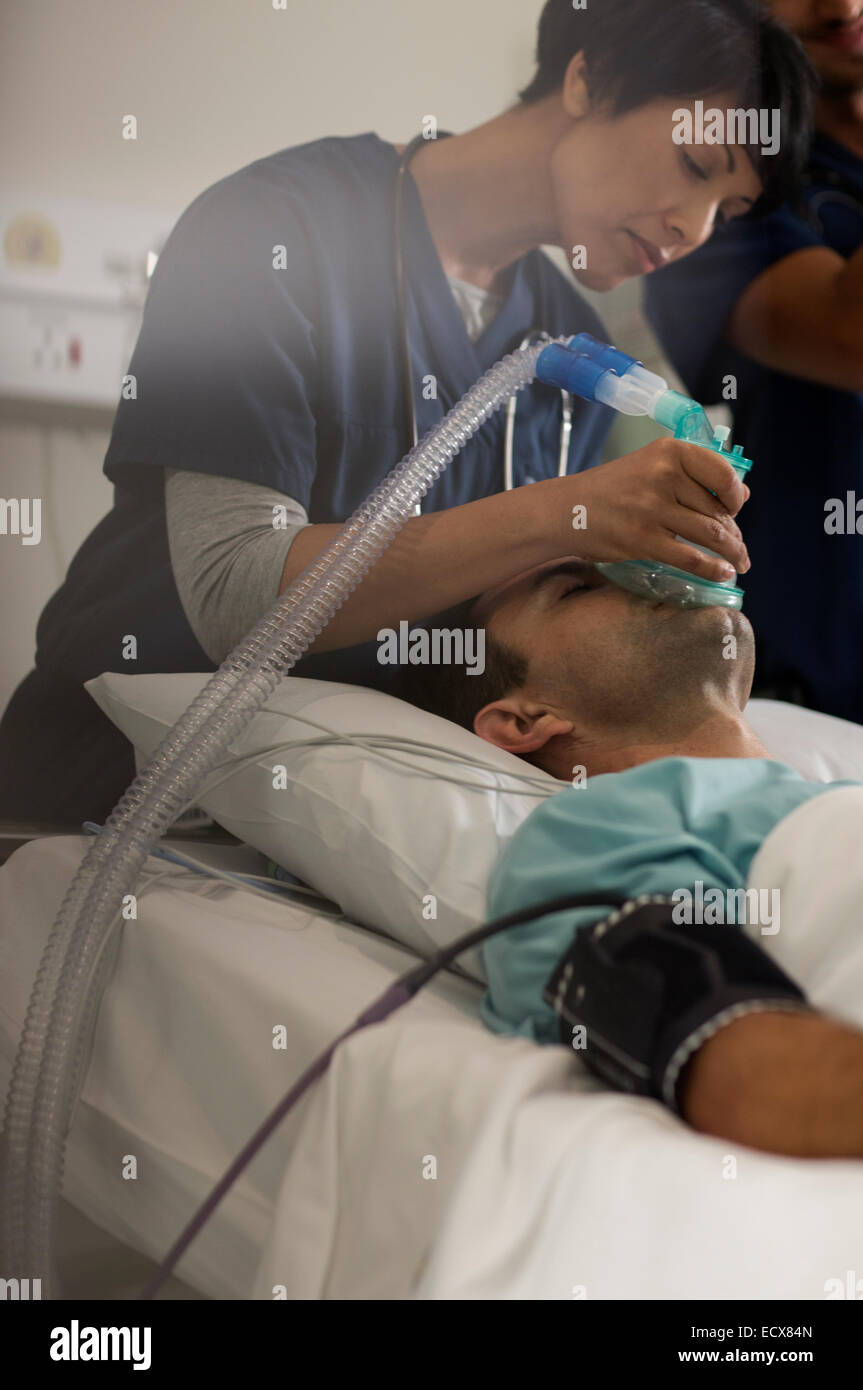 Medico tenendo le maschere di ossigeno su maschio della bocca del paziente in unità di terapia intensiva Foto Stock