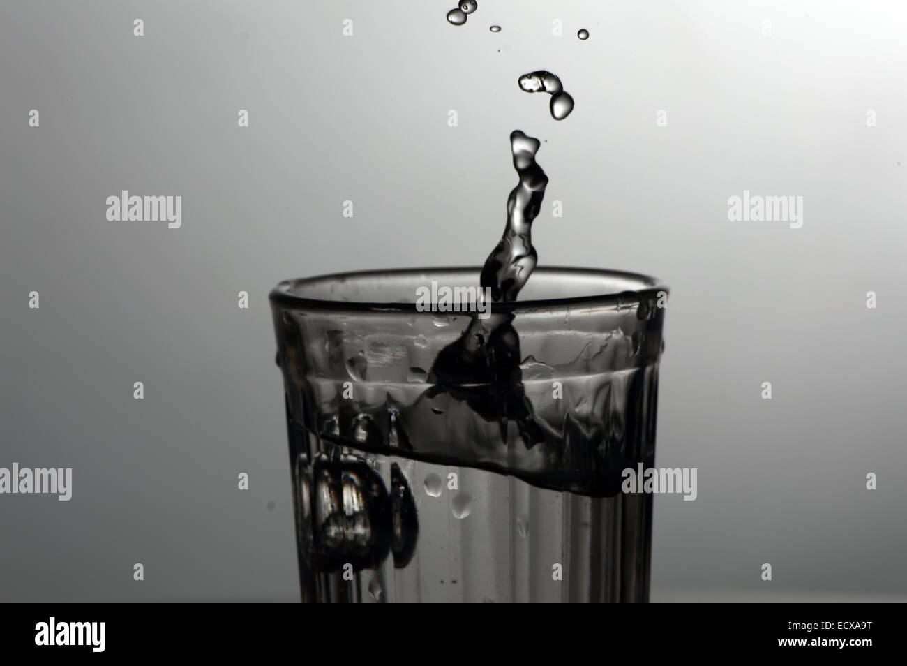 Gli spruzzi e le gocce di acqua in vetro sfaccettate Foto Stock