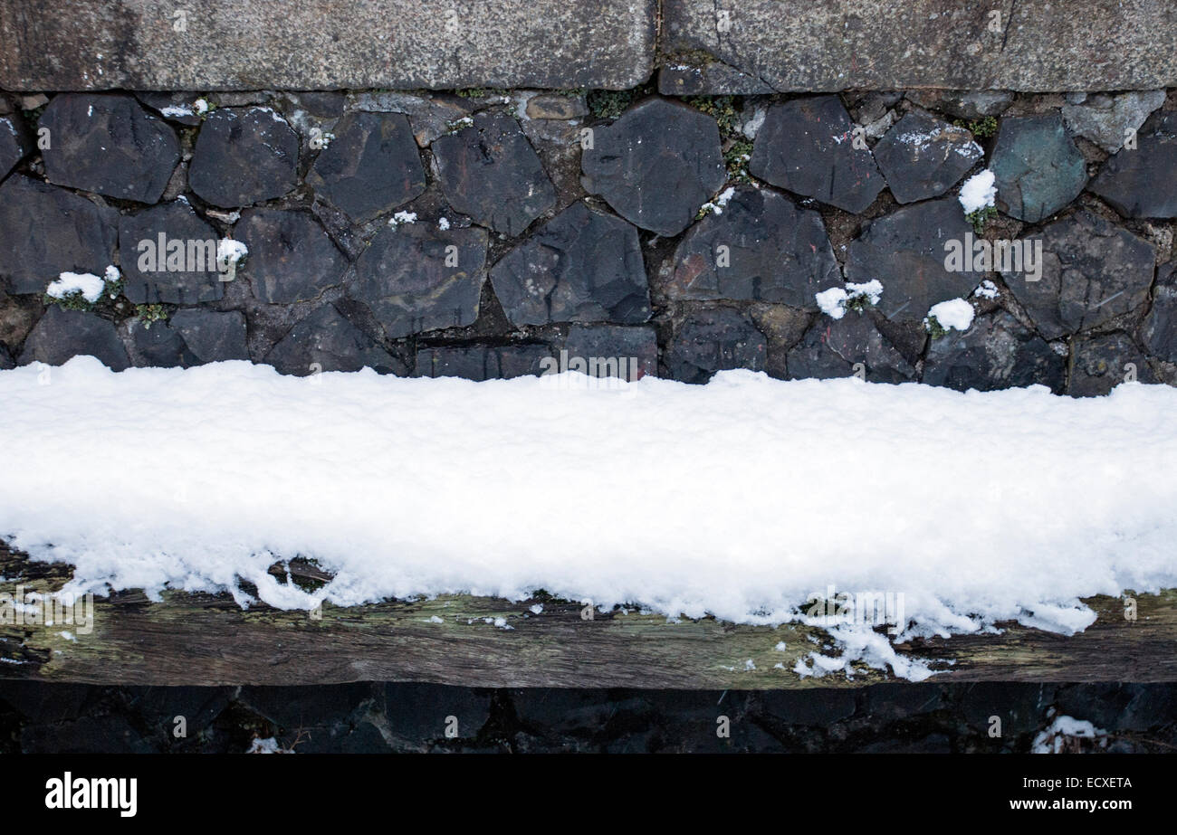 Verticale parete quay con grandi ciottoli, i blocchi di granito e coperta di neve weathered trave in legno Foto Stock