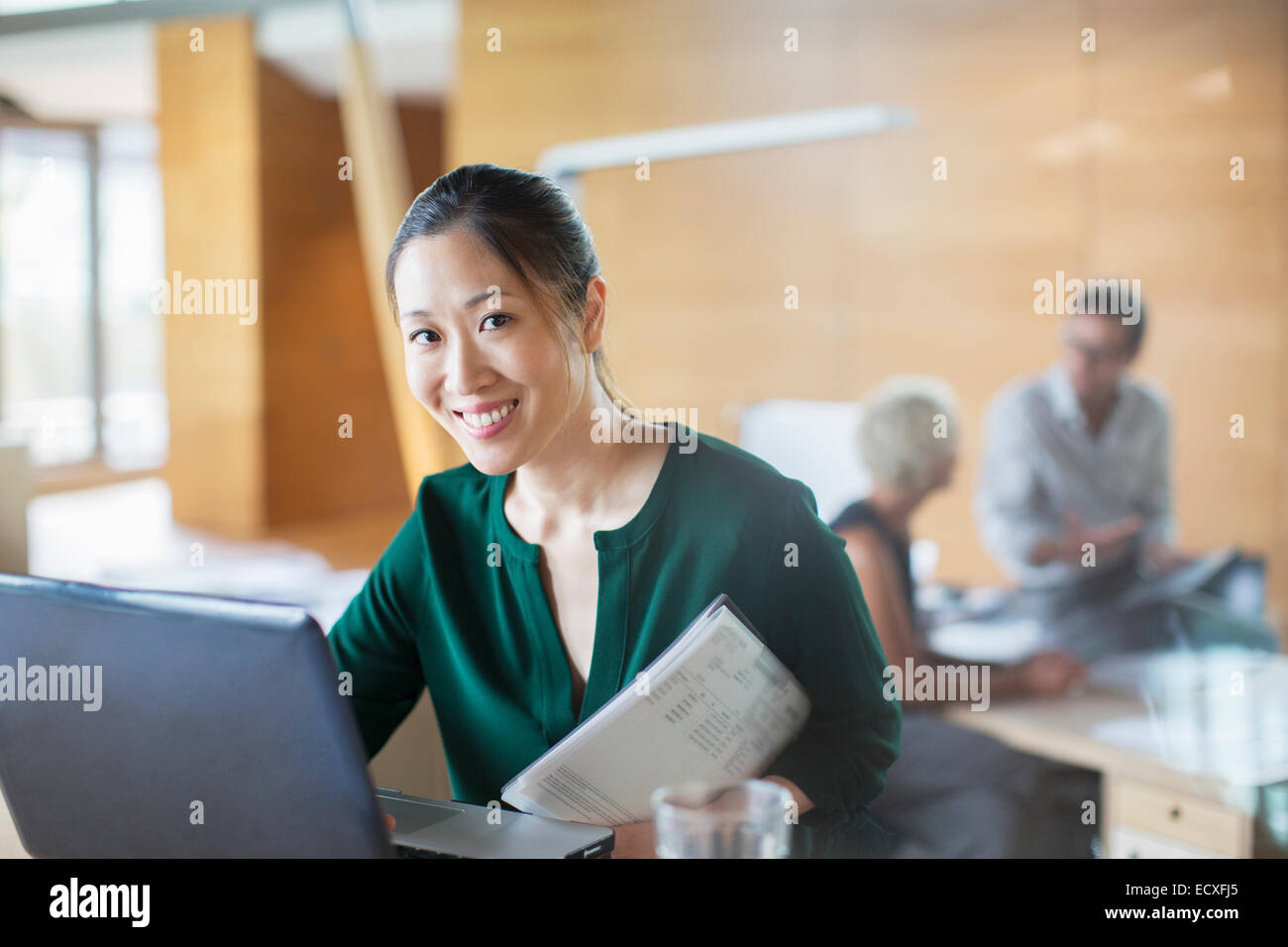 Imprenditrice sorridente con notebook in ufficio Foto Stock