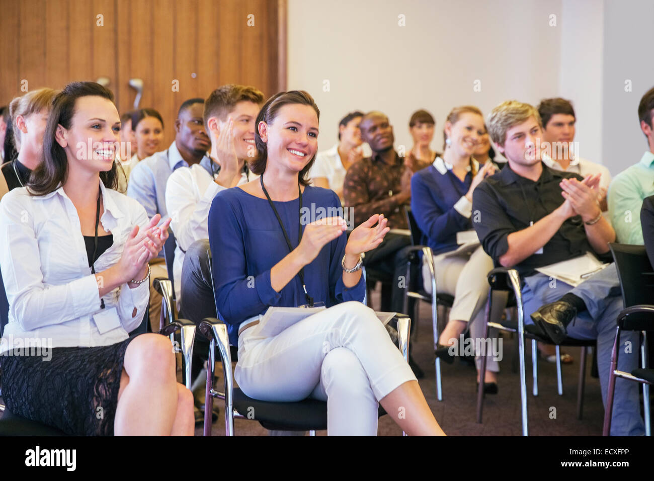 Ritratto di due donne sorridente in seduta tra gli altri partecipanti alla conferenza in sala conferenze, applaudendo Foto Stock