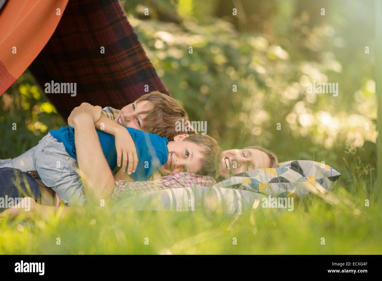 Padre e figli insieme rilassante vicino alla tenda da campeggio Foto Stock