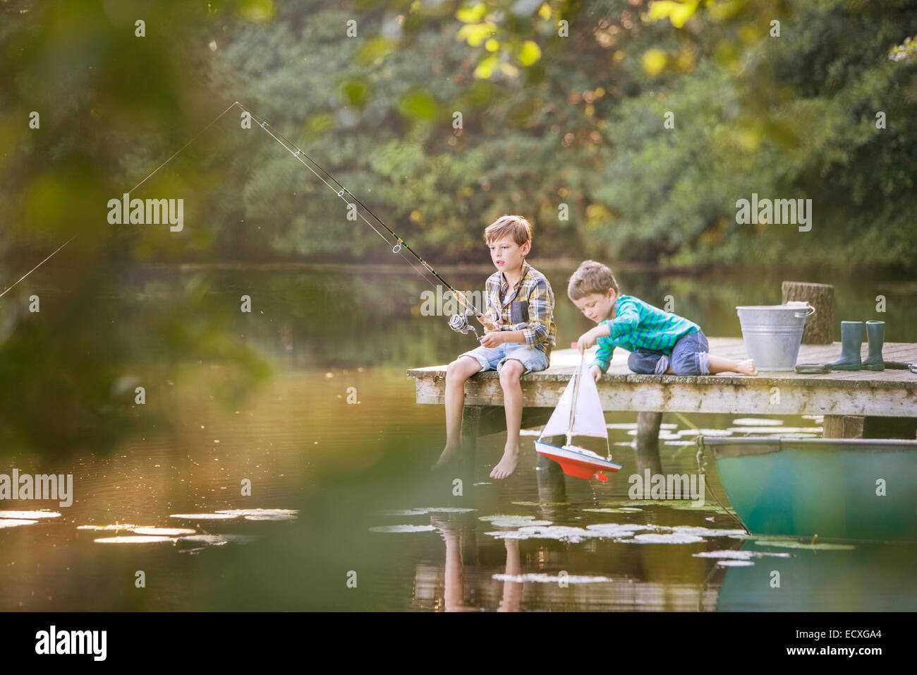 I ragazzi di pesca e di giocare con il giocattolo in barca a vela sul lago Foto Stock