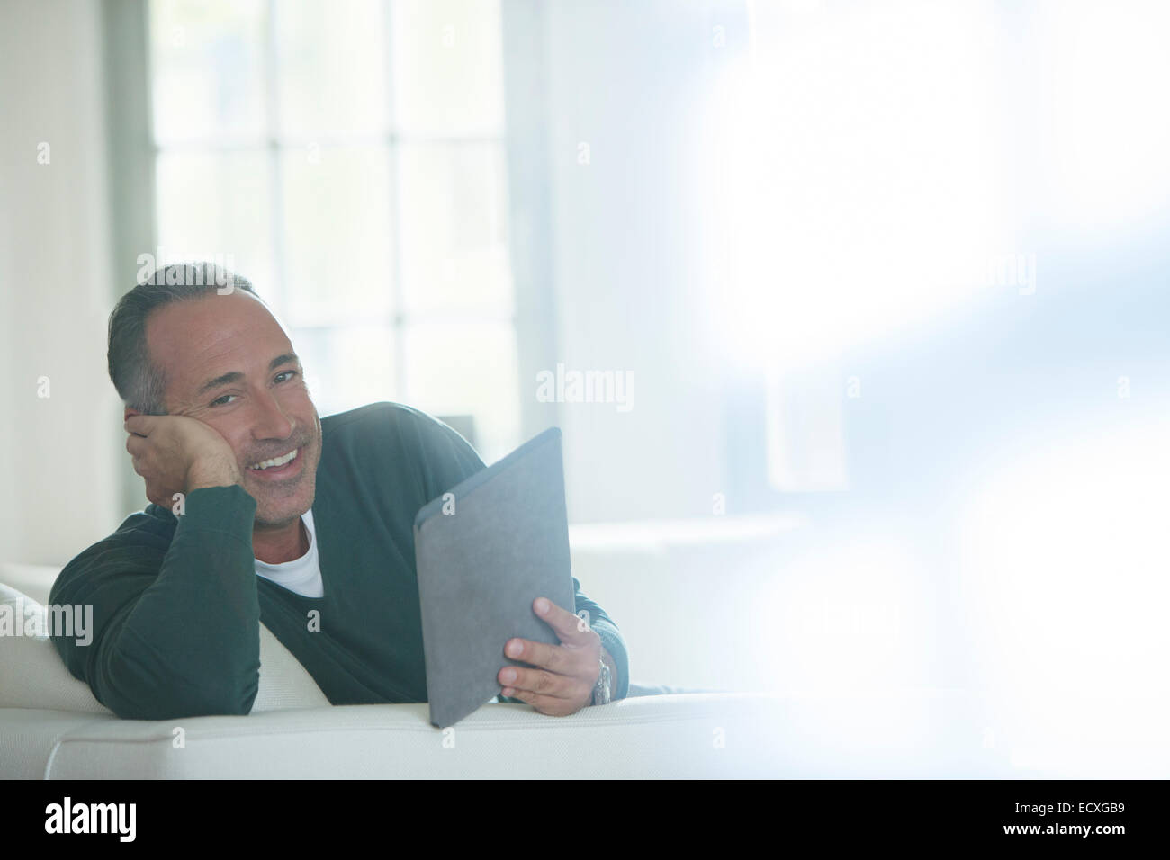 Uomo anziano con tavoletta digitale sul divano Foto Stock