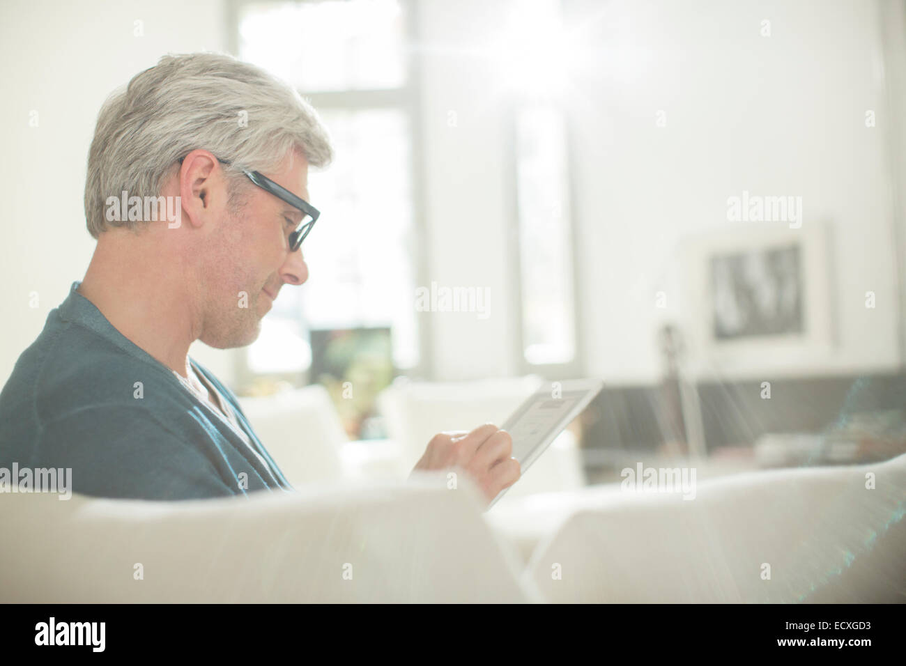 Uomo anziano con tavoletta digitale sul divano Foto Stock
