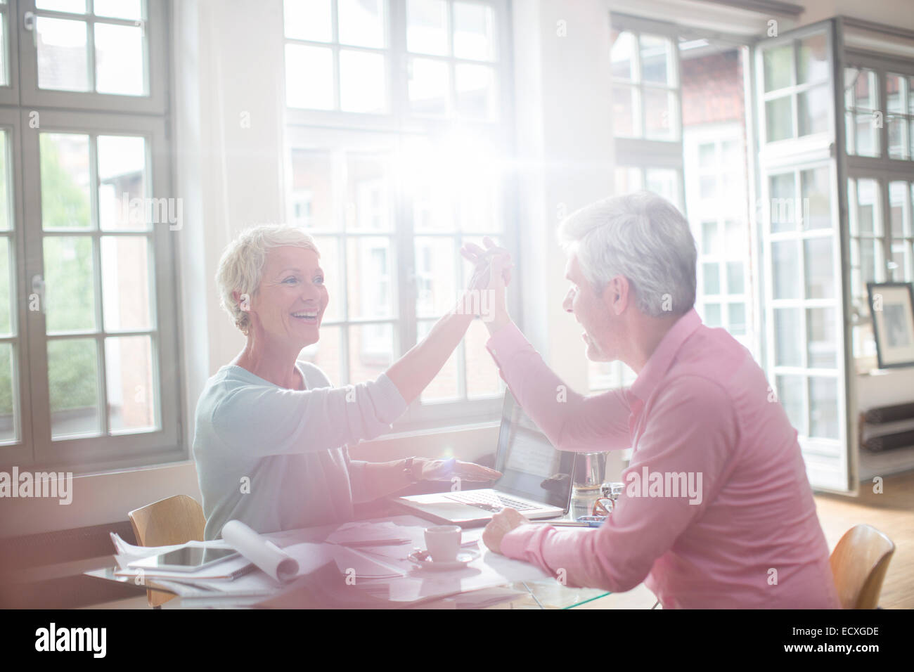 La gente di affari ad alta fiving a home office desk Foto Stock