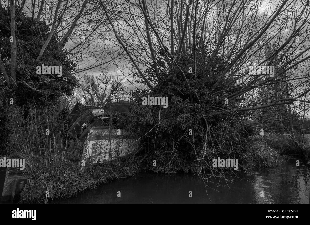 Una barca capovolta giace dimenticato su una riva di un fiume. Foto Stock