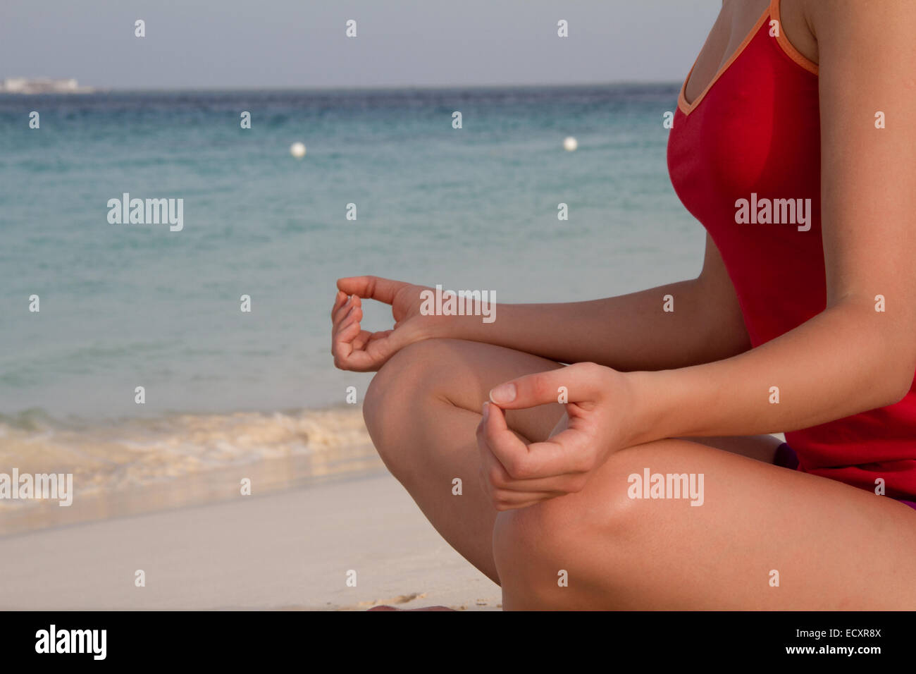 Giovani donne a praticare lo yoga e la meditazione sulla spiaggia con un mare turchino dei Caraibi come sfondo Foto Stock