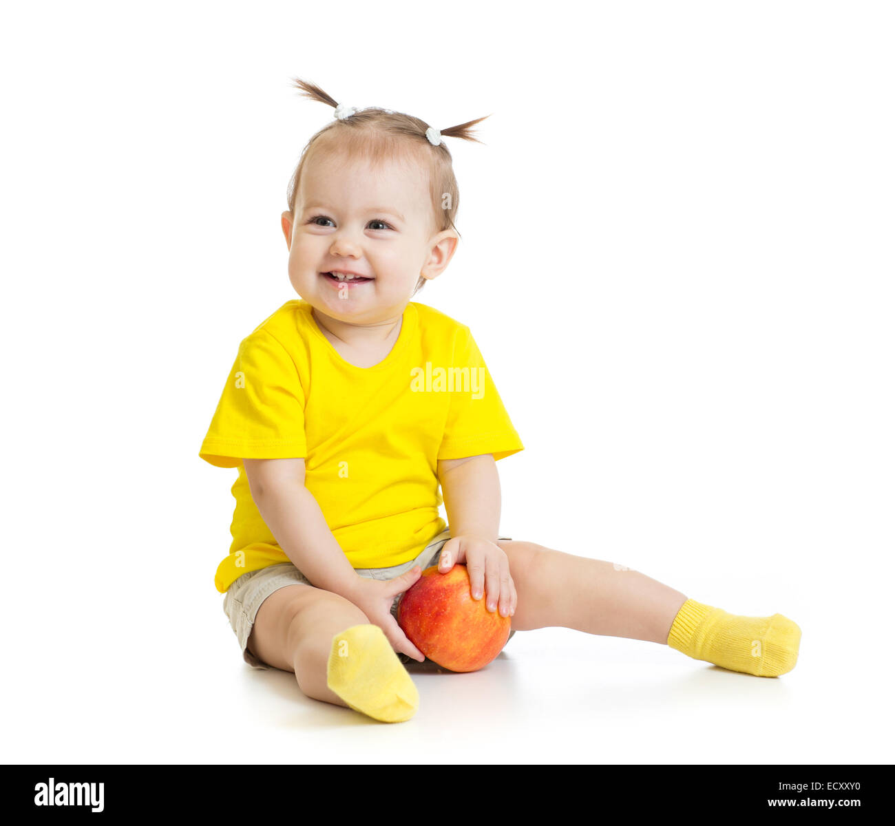 Baby mangiare mela rossa seduta sul pavimento isolato Foto Stock